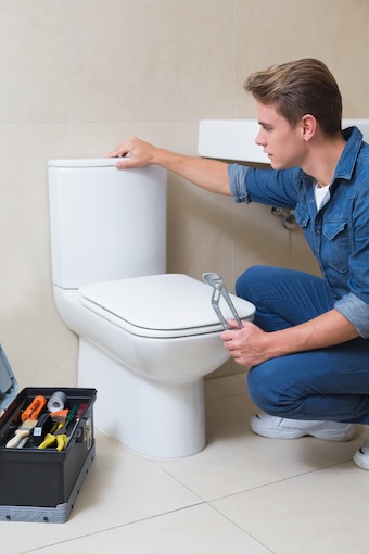 Toilet Installation and Repair Plumber with toolbox doing toilet reparation