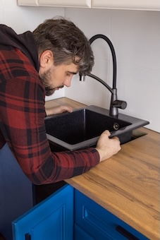 Sink Installation Plumber installing sink into wooden countertop in kitchen